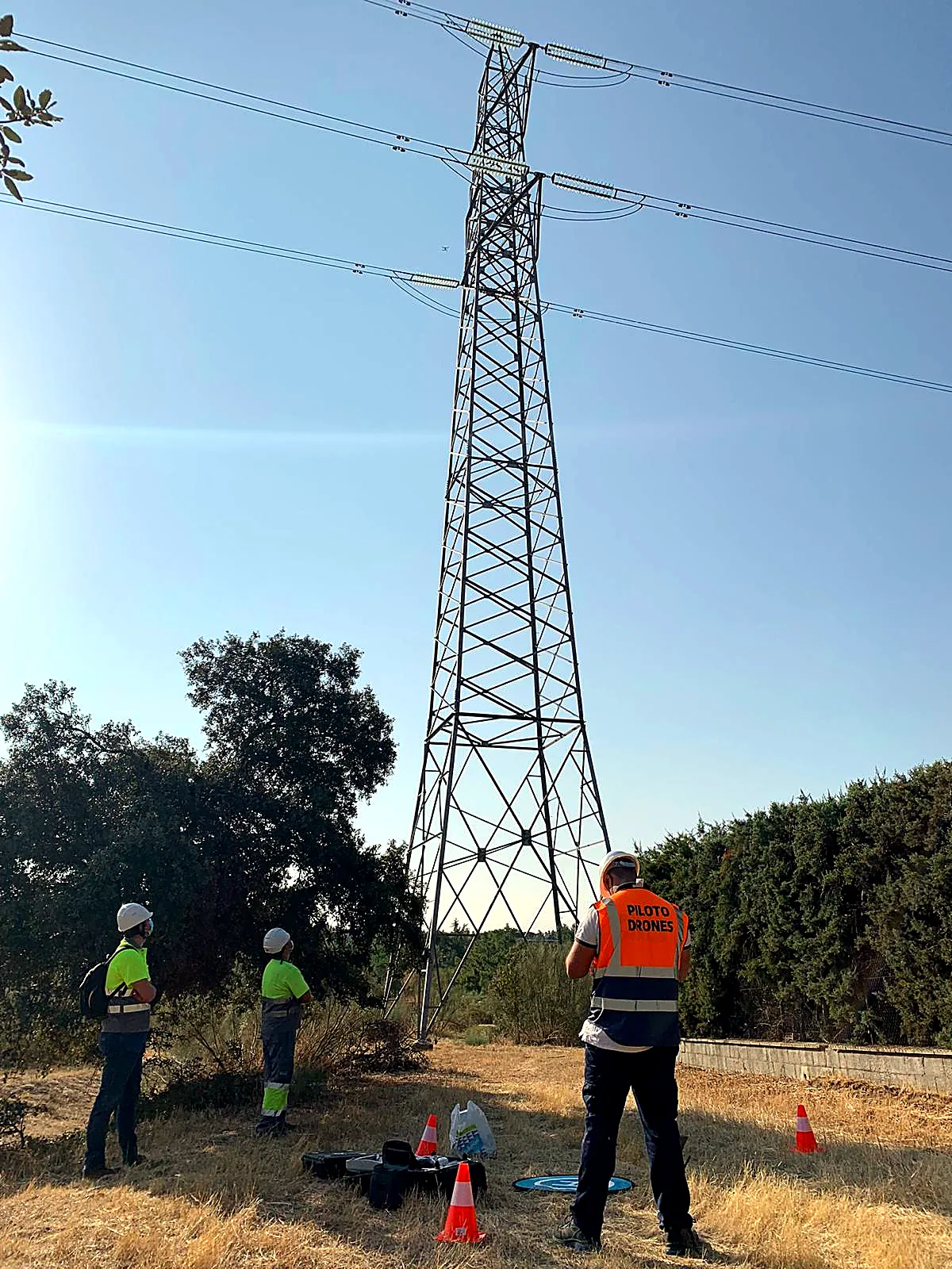 Equipo de pilotos inspeccionando una línea eléctrica de alta tensión con dron